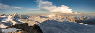 Vergletscherte Hochgebirgslandschaft, Panoramabild, die Sonne steht recht tief und wirft Schatten auf die Eisflächen.