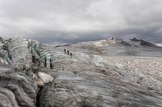 Drei Personen in aperer Gletscherlandschaft.
