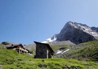 Hütte vor schneebedecktem Gipfel.