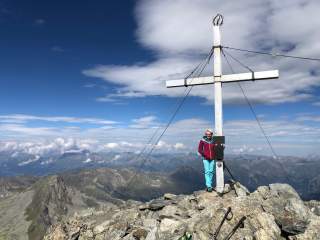 Renate vor einem Gipfelkreuz.