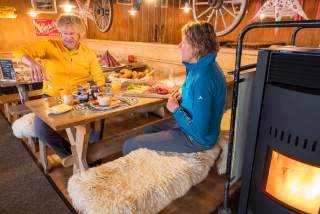 Zwei Menschen sitzen an rustikalem Holztisch und frühstücken