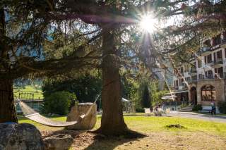 Hotelgarten mit Hängematte, die Sonne blitzt durch die Bäume