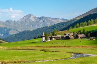 Traditionelles Schweizer Dorf mit Bergkulisse und Bach im Vordergrund