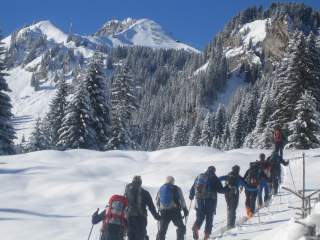 Gruppe von Menschen auf Skitour läuft durch verschneite Winterlandschaft