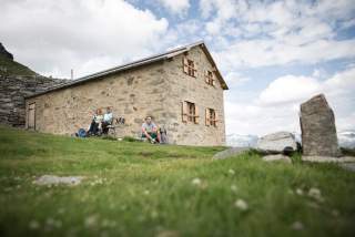 Drei Wanderer*innen vor der restaurierten Alten Prager Hütte.