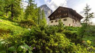 Hütte inmitten von grüner Landschaft und Bergen