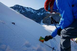 Mann misst Hangsteilheit im Schnee mit DAV SnowCard