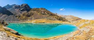 Türkisgrüner Bergsee mit kleiner Hütte