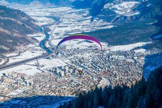 Ein Gleitschirmflieger über dem verschneiten Rheintal und über Chur.
