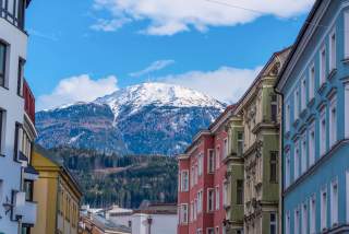 Am Ende einer Straße mit vielen farbigen Hausfassaden ist ein schneebedeckter Berg zu sehen.