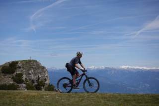 Mountainbiker im Hintergrund verschneite Gipfel.