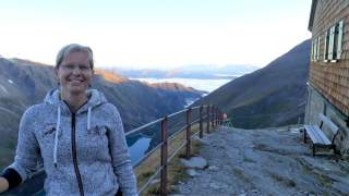 Frau neben Hütte mit Ausblick ins Tal
