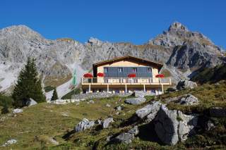 Berghütte vor schroffen Gipfeln