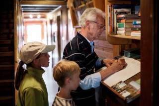 Mann und zwei Kinder stehen vor Hüttenbuch und tragen sich ein
