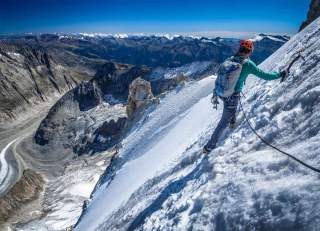 Person auf Hochtour mit Seil und Pickel an steiler Schneewand