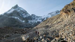 Zwei Bergsteiger steigen über Geröllfelder, im Hintergrund das Matterhorn