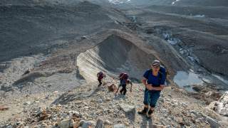Auf der nördlichen Seitenmoräne des Zmuttgletschers geht es für drei Bergsteiger steil hinauf. Tief unten die Reste des ehemals mächtigen Eisstroms.