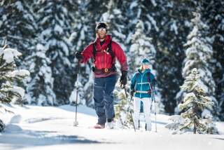 Zwei Menschen auf Skitour in verschneitem Wald