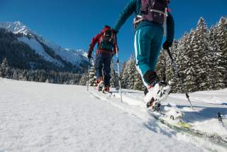 Zwei Personen auf Skitour auf die Berge zu laufend von hinten fotografiert