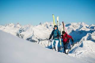 Zwei Menschen gehen mit Ski den Berg hoch