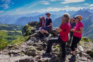 Menschen stehen auf Gipfel und bewundern den Ausblick