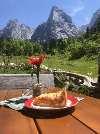 Hüttenterrasse mit Kuchen auf dem Tisch und Blick auf Felswände