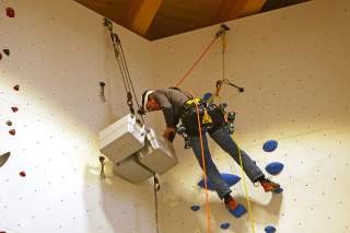 Routenbauer sucht Material aus einer Kiste oben am Top einer Kletterroute.