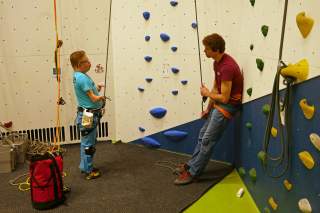 Paraclimber und Routenbauer sind vor einer Kletterwand ins Gespräch vertieft.