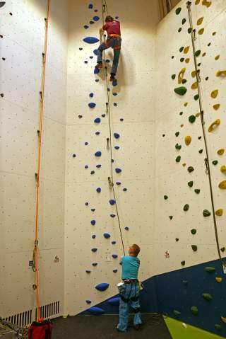 Routenbauer klettert seine Route im Toprope, Paraclimber sichert.