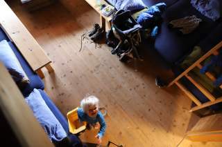 Kleinkind hält Spielzeug-LKW in der Hand. Blick aus der Vogelperspektive vom Stockbett auf das Kind.