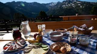 Gedeckter Frühstückstisch vor Bergpanorama.