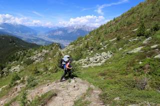 Mutter wandert mit Kraxe den Berg hoch