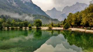 Blick auf grün schimmernden Bergsee mit Gipfeln im Hintergrund