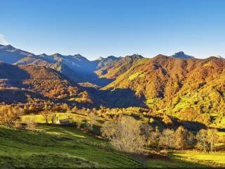 Blick über ein grünes Tal mit mittelhohen Bergen.