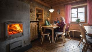 Drei Menschen sitzen gemütlich in Berghütte zusammen