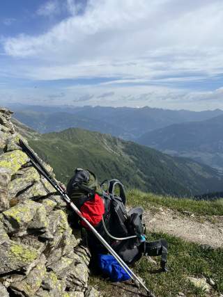Rucksack und Wanderstöcke auf Wanderweg