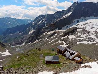 Blick auf Hütte im Gebirge, Helikopter liefert gerade Lebensmittel an