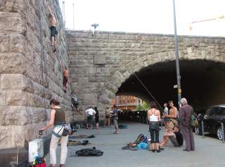 Mehrere, überwiegend junge Menschen klettern an einer Brücke aus Muschelkalk.