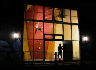 Blick durch eine Glasfassade auf eine Kletterwand.
