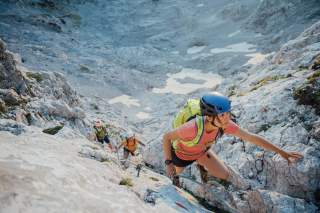 Drei Menschen an einem Klettersteig.