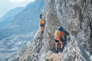 Drei Menschen im Klettersteig in felsiger Gebirgslandschaft Drei Menschen im Klettersteig in felsiger Gebirgslandschaft