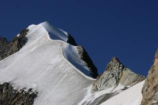 Schneebedeckter Berggrat vor blauem Himmel