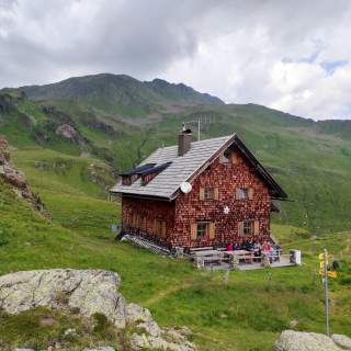Eine holzverschindelte Berghütte.