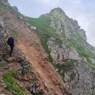 Ein Wanderer an einem steilen Berghang, an dem eine Mure abgegangen ist.