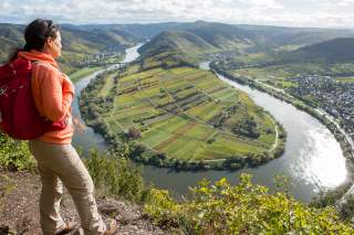 Frau steht über der Moselschleife und genießt die Aussicht