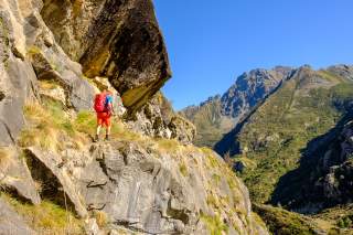 Mensch wandert auf schmalem Pfad durch sommerliche Bergwelt