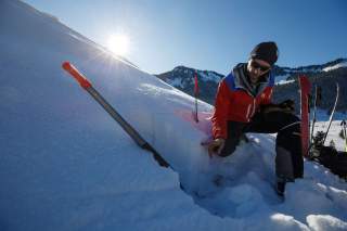 Mann erklärt Schneeprofil am Berg Mann erklärt Schneeprofil am Berg