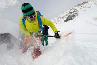 Mensch gräbt verschüttete Person im Schnee aus