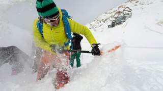 Mensch gräbt verschüttete Person im Schnee aus