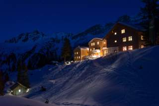 Während die Nacht einbricht, ist die Lindauer Hütte hell erleuchtet.